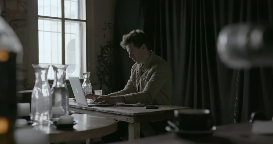 A man uses his keyboard by the window