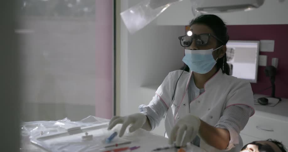 A doctor sets up her tools to begin dentist work