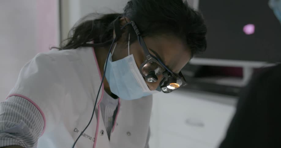 A dentist works on a patient with an assistant