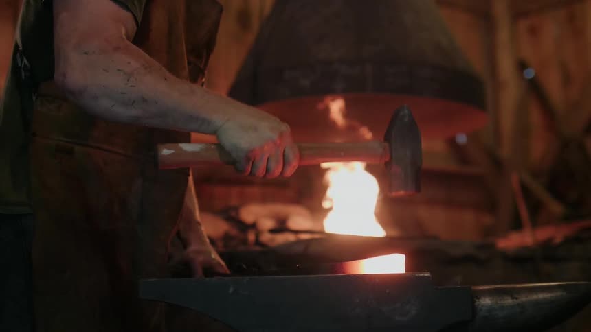 A blacksmith hammers on a glowing steel rod