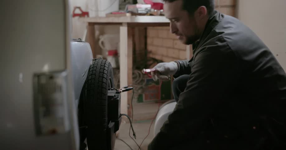 A man works on a scooter in a garage