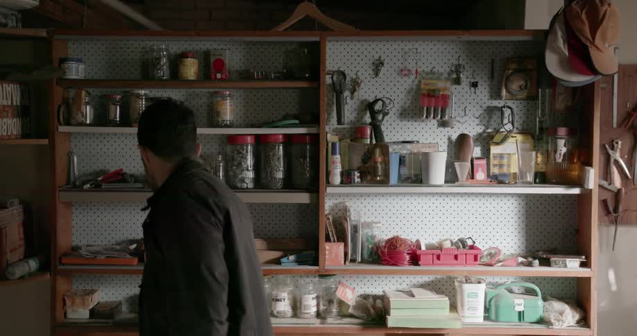 Man looks at tools on a garage shelf