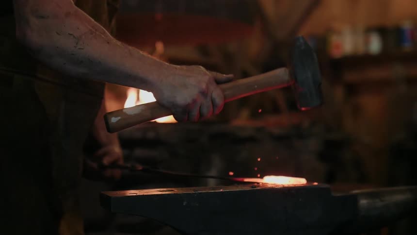 A blacksmith hammers a piece of hot metal