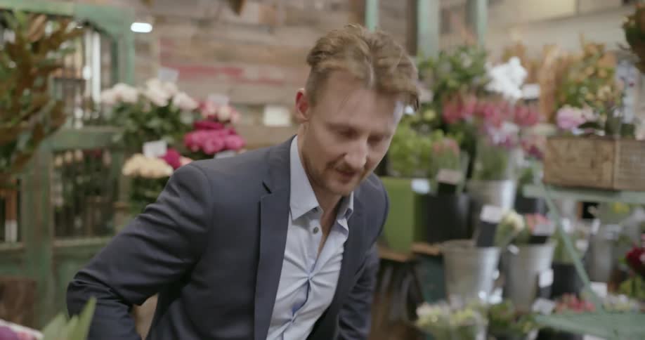 A man purchases a bouquet of roses from a florist