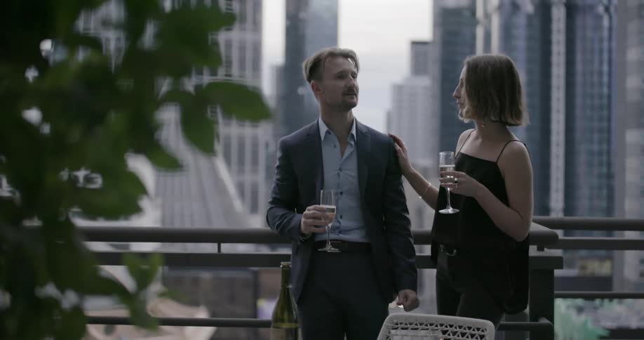 A man and woman drink champagne on a balcony