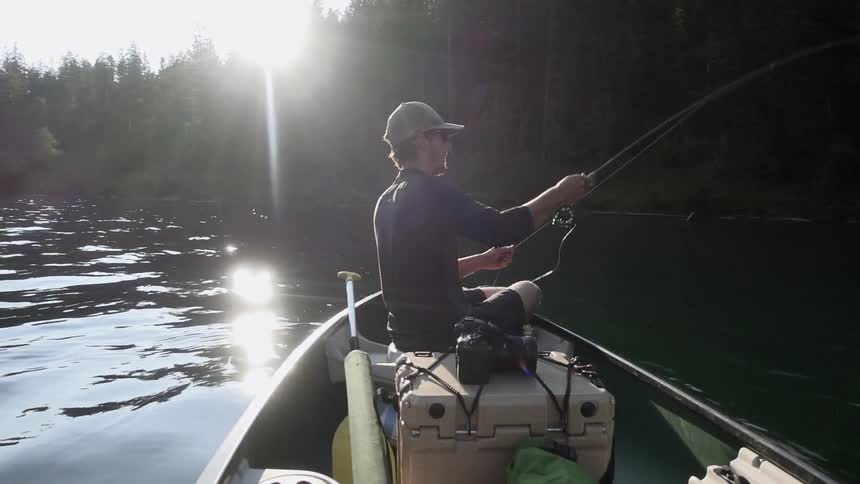 A man fishes from a boat on a sunny day