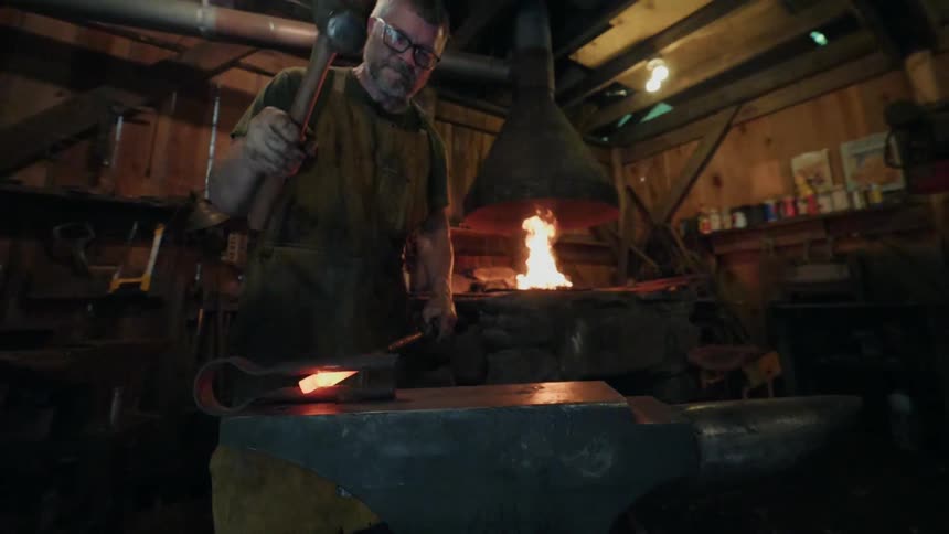 A blacksmith hammers a piece of hot metal