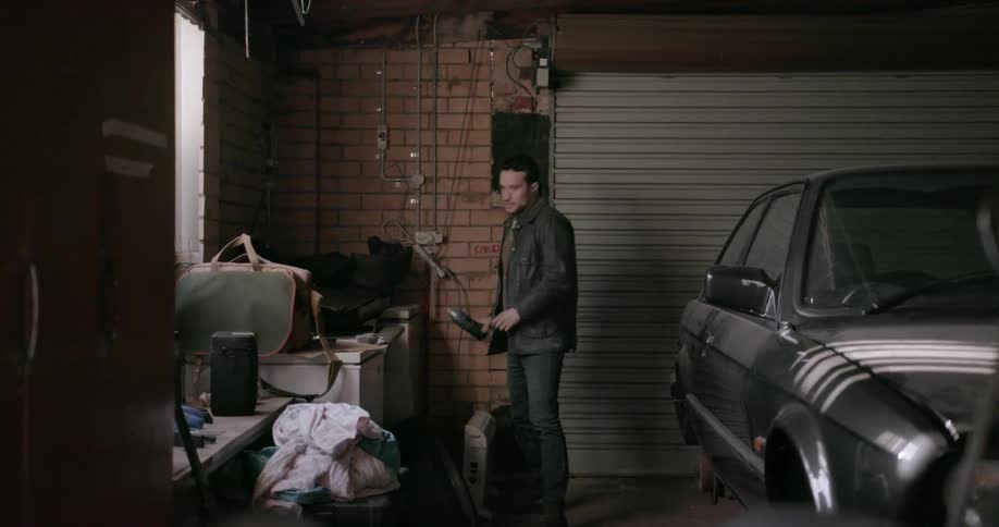A man picks up a can of spray paint in a garage