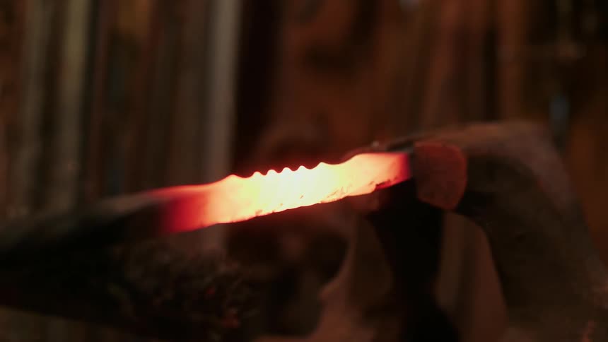 Blacksmith rubs a piece of hot metal with a brush