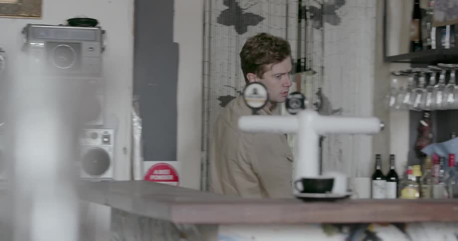 Man walks by a wall of stereos in a bar