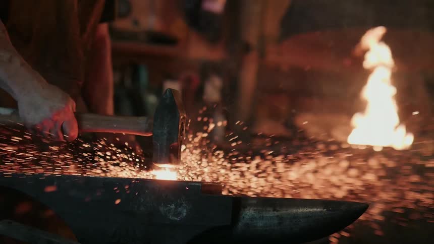A blacksmith slams his hammer down on the anvil
