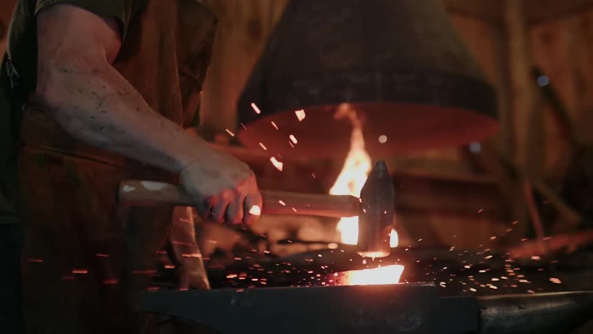 A blacksmith hammers metal giving sparks all over