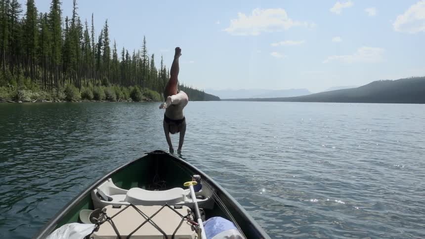 A woman dives off the boat into the lake