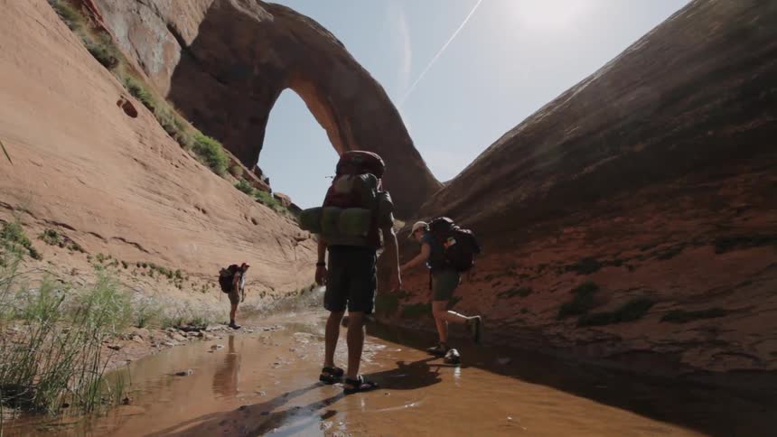 Backpackers hike in a desert canyon