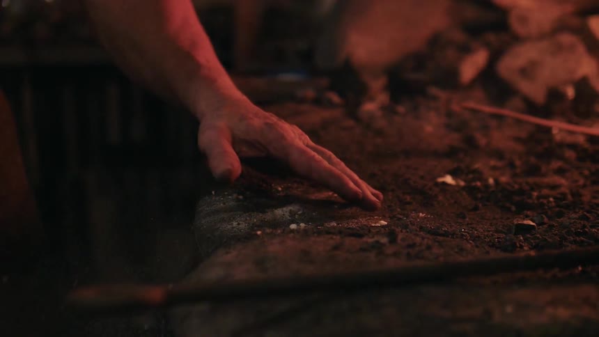 A person brushes ashes off a stone