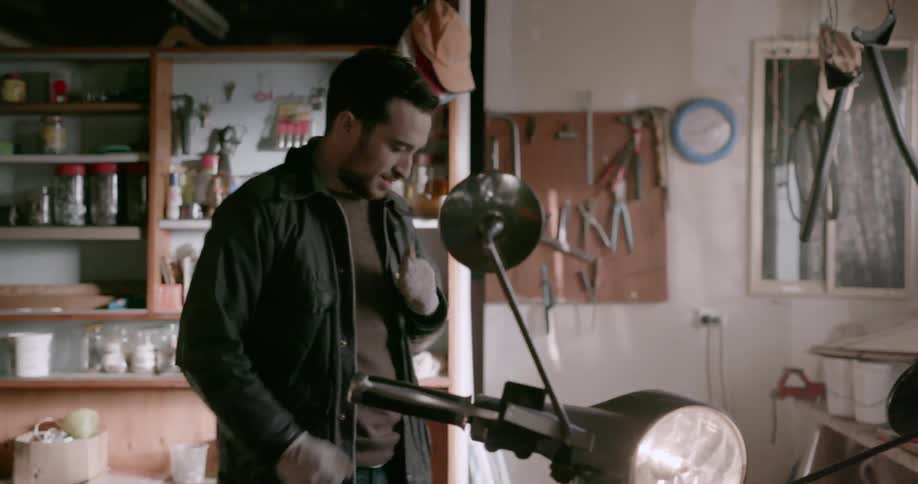 A man starts up a scooter in his garage
