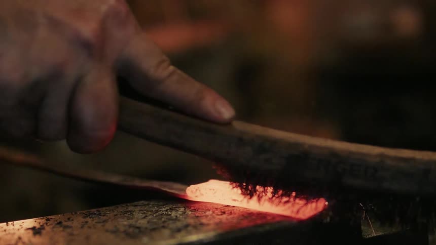 A man uses a brush on hot metal