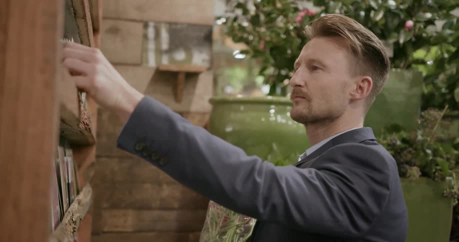 A man looks at cards while holding a bouquet of flowers in a store