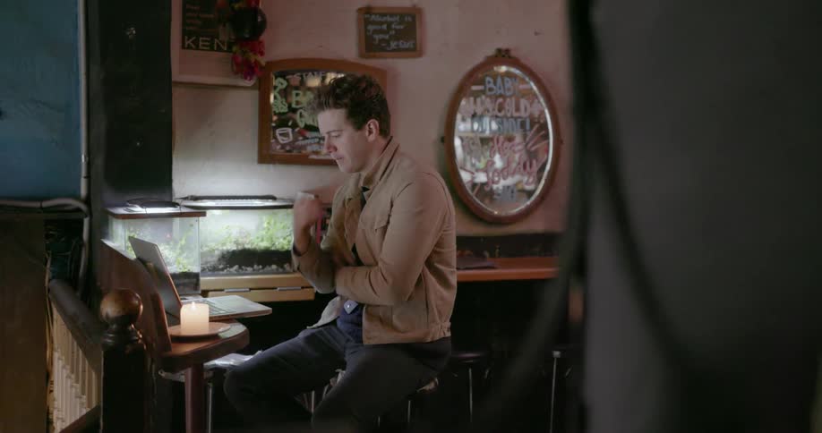 A man is typing on his keyboard by a fish tank