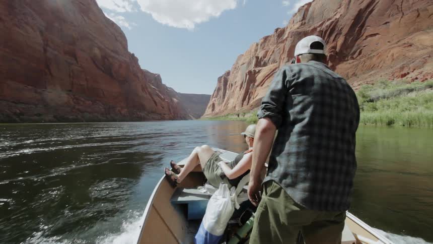 A couple boat through a canyon river on a sunny day