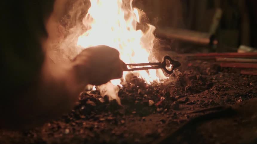 A person stirs the fire with tongs