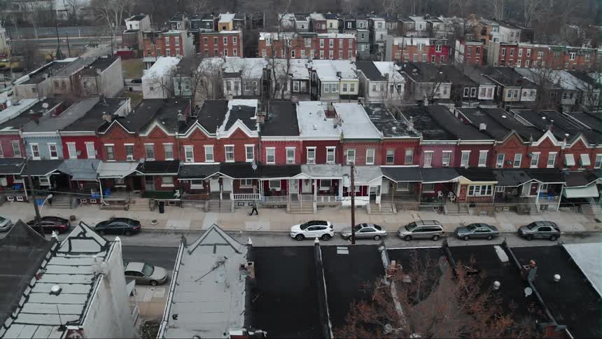 A person walks down the sidewalk past a row of houses
