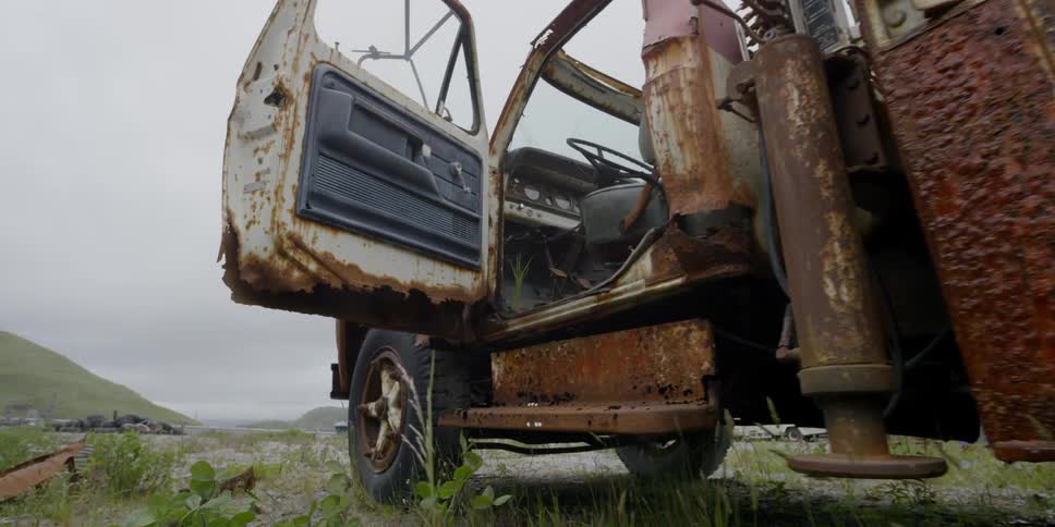 The door of an abandoned and rusted truck is open
