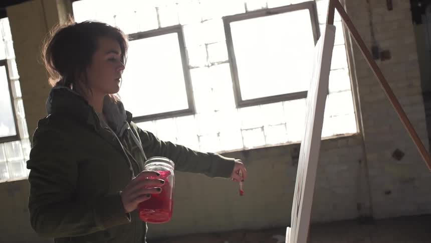 A young woman brushing red paint onto a canvas