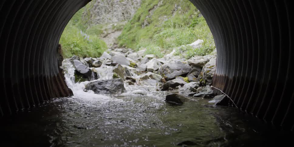 A dark tunnel opens up to water cascading over rocks