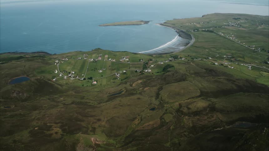 Houses on grassy hilly land near water