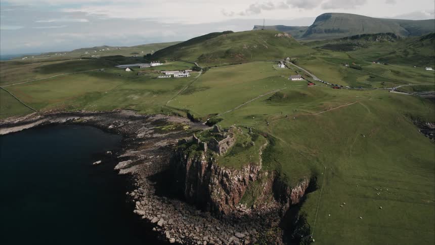 The remains of a castle on a green hilltop near the ocean's edge