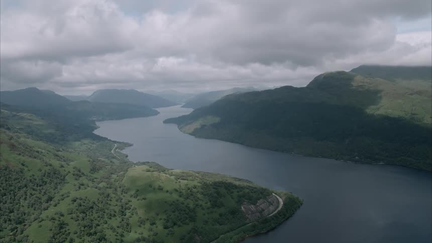 A loch (Lake) curves around hills on a cloudy day