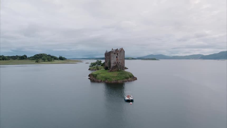 A small castle sits on an island in the middle of a lake