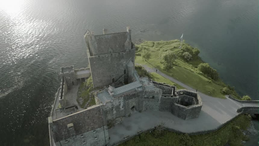 A castle sits atop a hill by the water