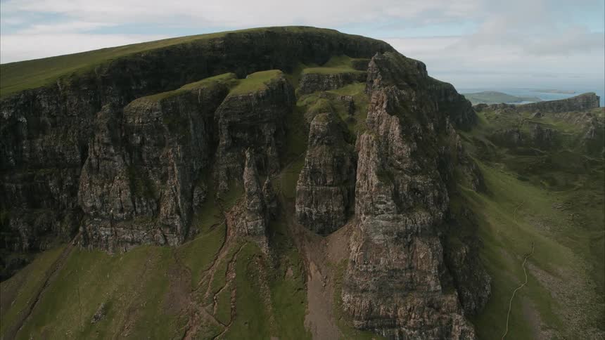 A steep rocky cliff juts up from a hillside