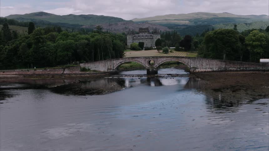 An old stone building sits next to a rippling lake