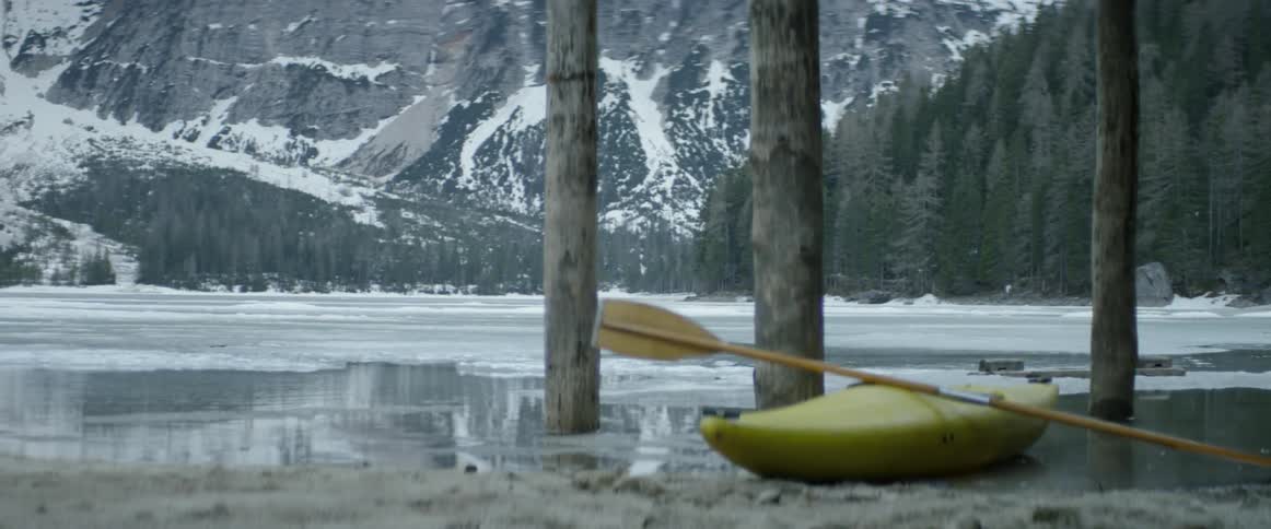 A kayak sits next to a mountain lake