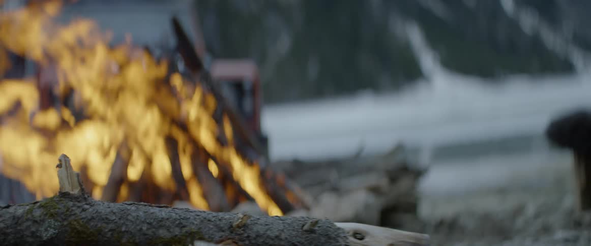 An ax is used to chop wood next to a campfire
