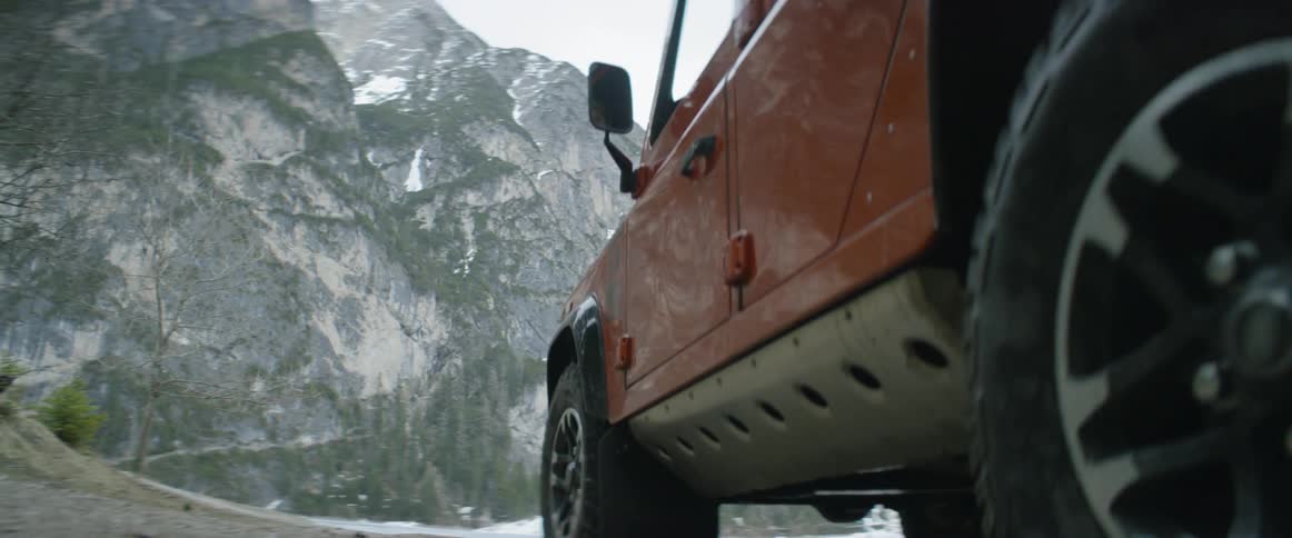 Jeep rolls through muddy water driving near mountains