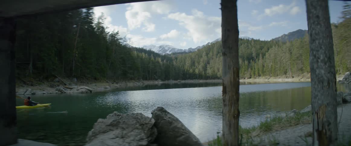 Someone in a kayak is rowing on a small lake
