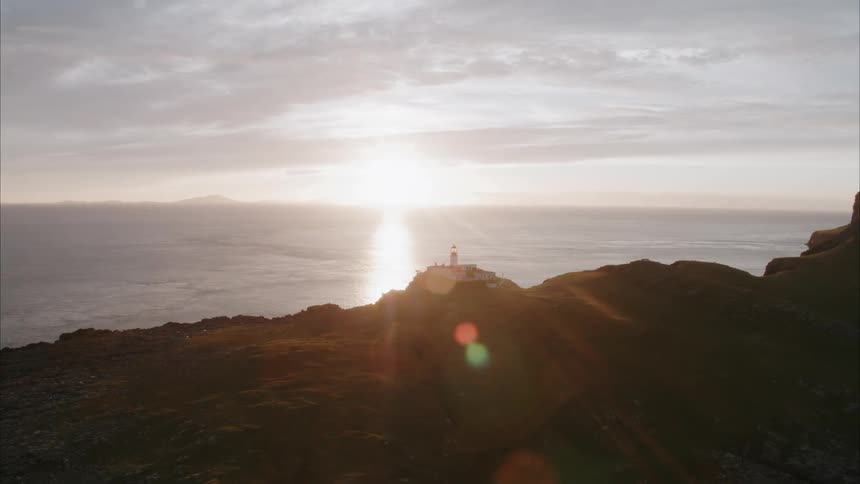 The sun sets over a lighthouse on the coast