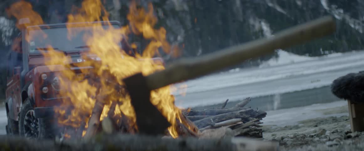 An ax sits next to a burning campfire