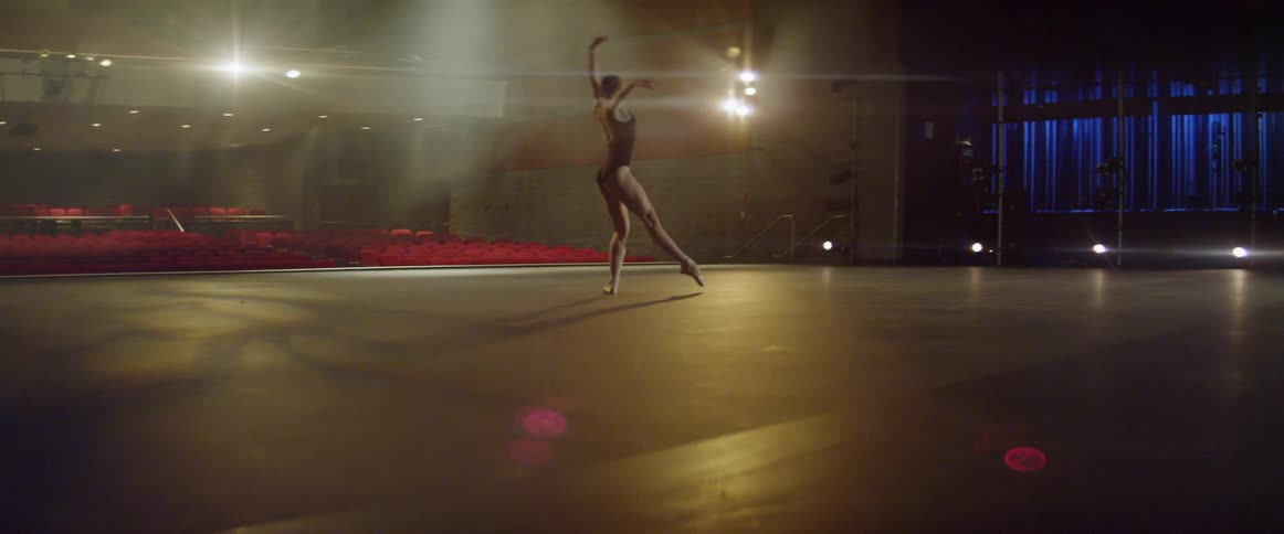 A ballet dancer is practicing on stage in an empty theater