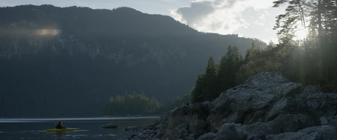 A person kayaks on a mountain lake