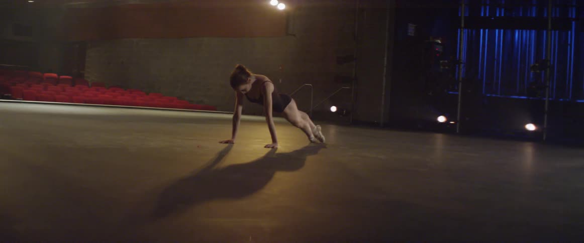 Woman dances in the middle of an empty auditorium stage