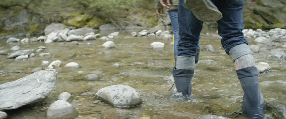 Hikers wade across a river