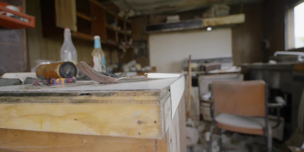 A spatula sits on the counter of an abandoned and destroyed kitchen