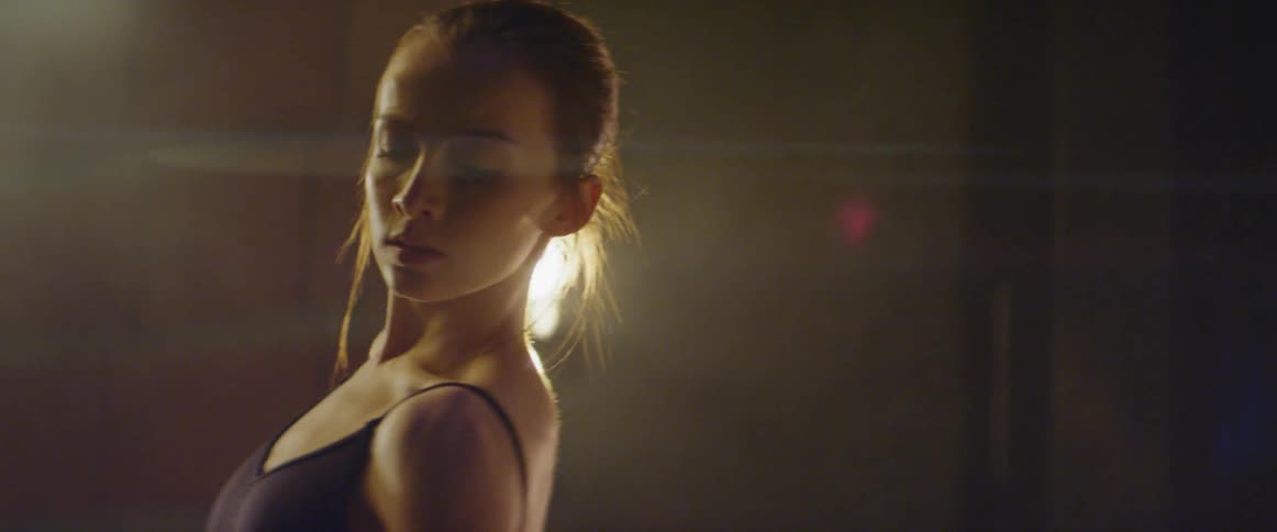 Young ballerina is dancing indoors in front of lights