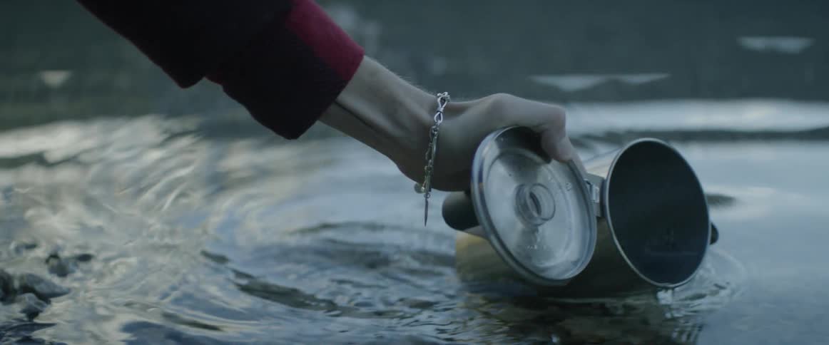 A person fills their pitcher from the lake