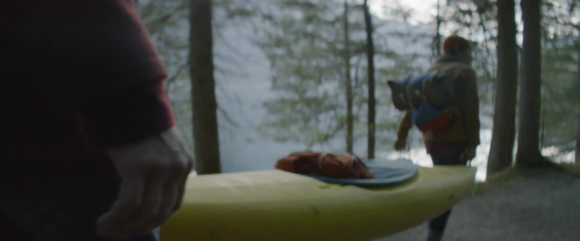 Hikers carry a kayak in a forest